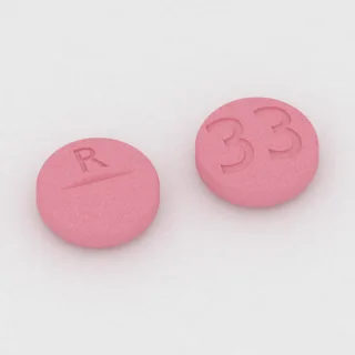 Clonazepam 0.5 mg Tablette: rosa, rund, 8 mm, mit Bruchkerbe, Prägung R auf der einen Seite und 33 auf der anderen.
